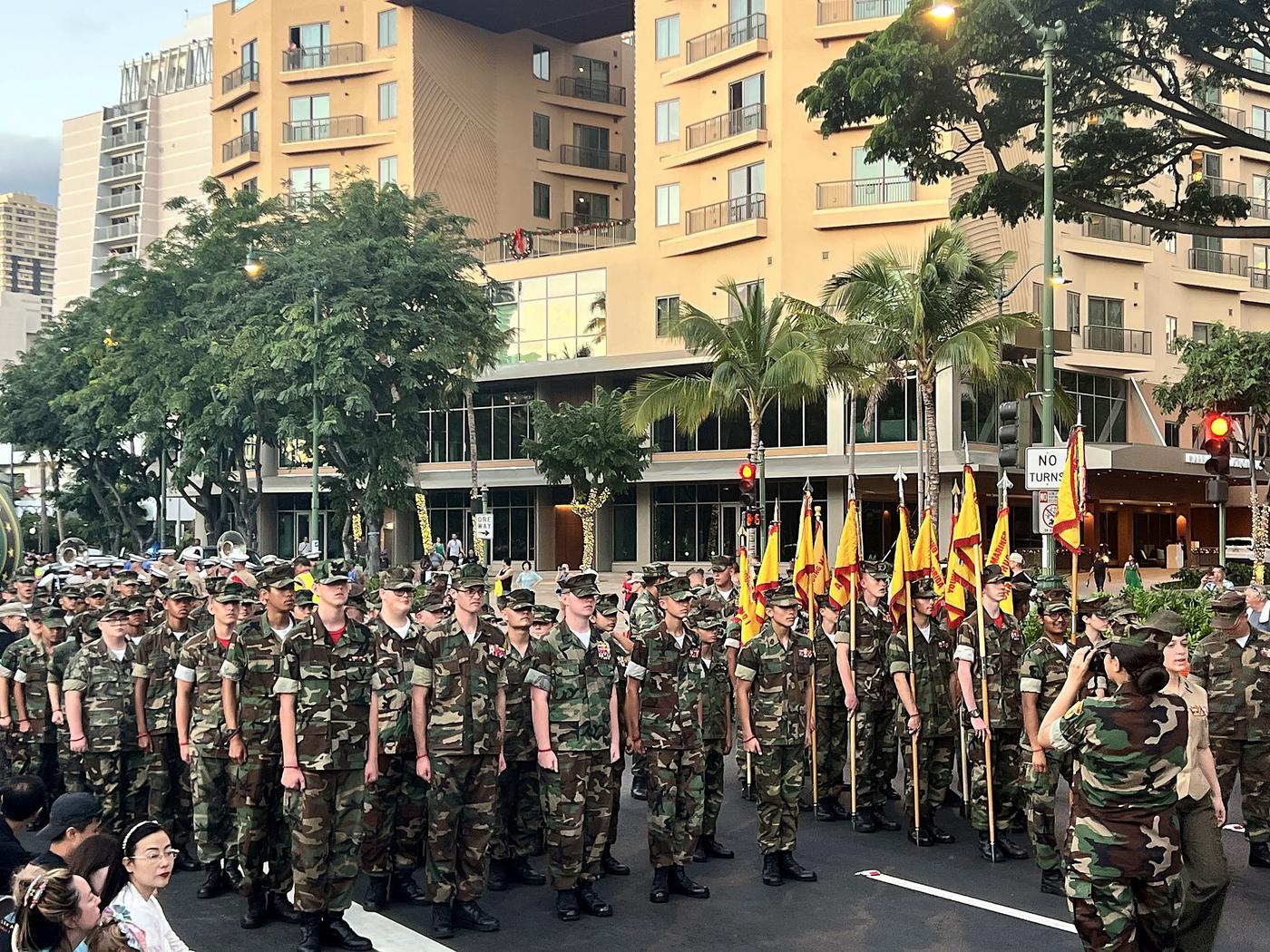 Young Marines standing in formation with unit guidons during the Waikiki parade